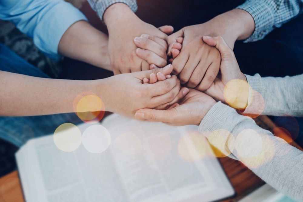 hands joined over a book