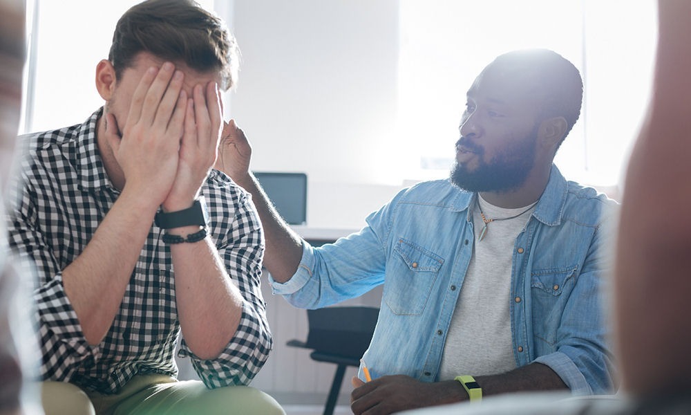 man covering his face while he is with support group