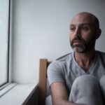 sad man sitting by a window with insomnia