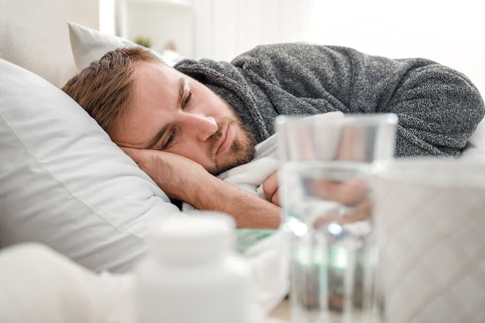 man in bed wondering how long his alcohol poisoning will last